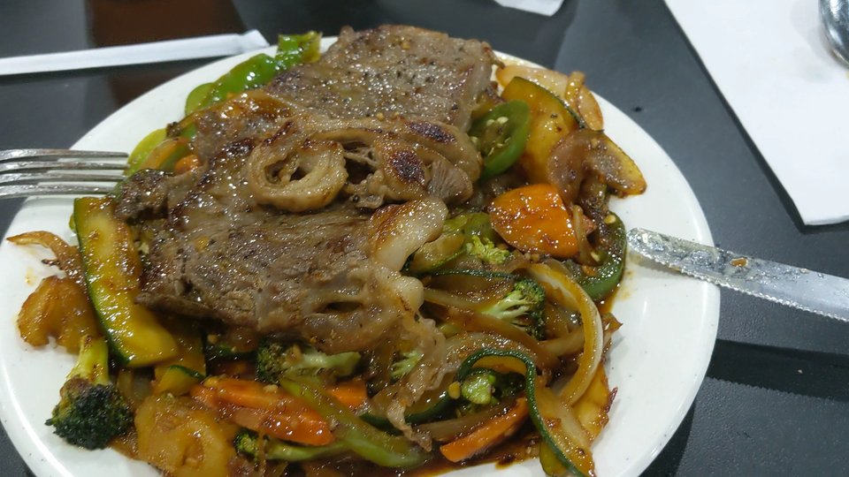 Teppanyaki grill station with seafood, vegetables, and steak.